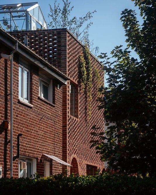 The house acts as a taller corner piece to the street, its mass lightened by perforated brickwork round the roof garden.