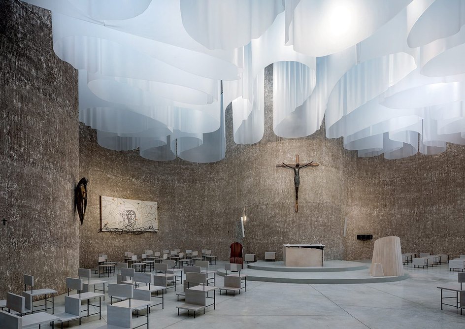 The church’s sculptural interior is lit through curving drapes hung from the ceiling.