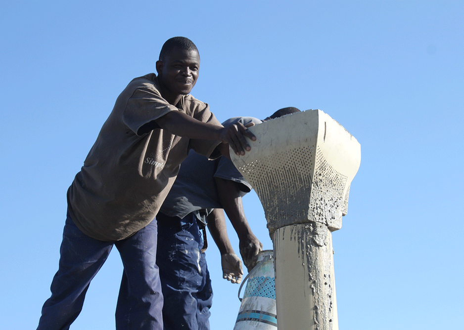 Table House under construction, funnel feeding concrete into the formwork of a PVC drainage pipe.