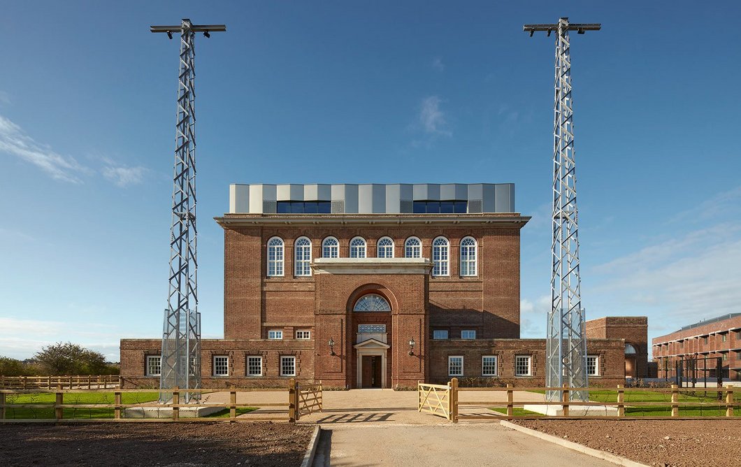 The former main east entrance of Rugby radio station, between two of the remaining, smaller transmitter masts. These have all been repurposed as external lighting rigs.