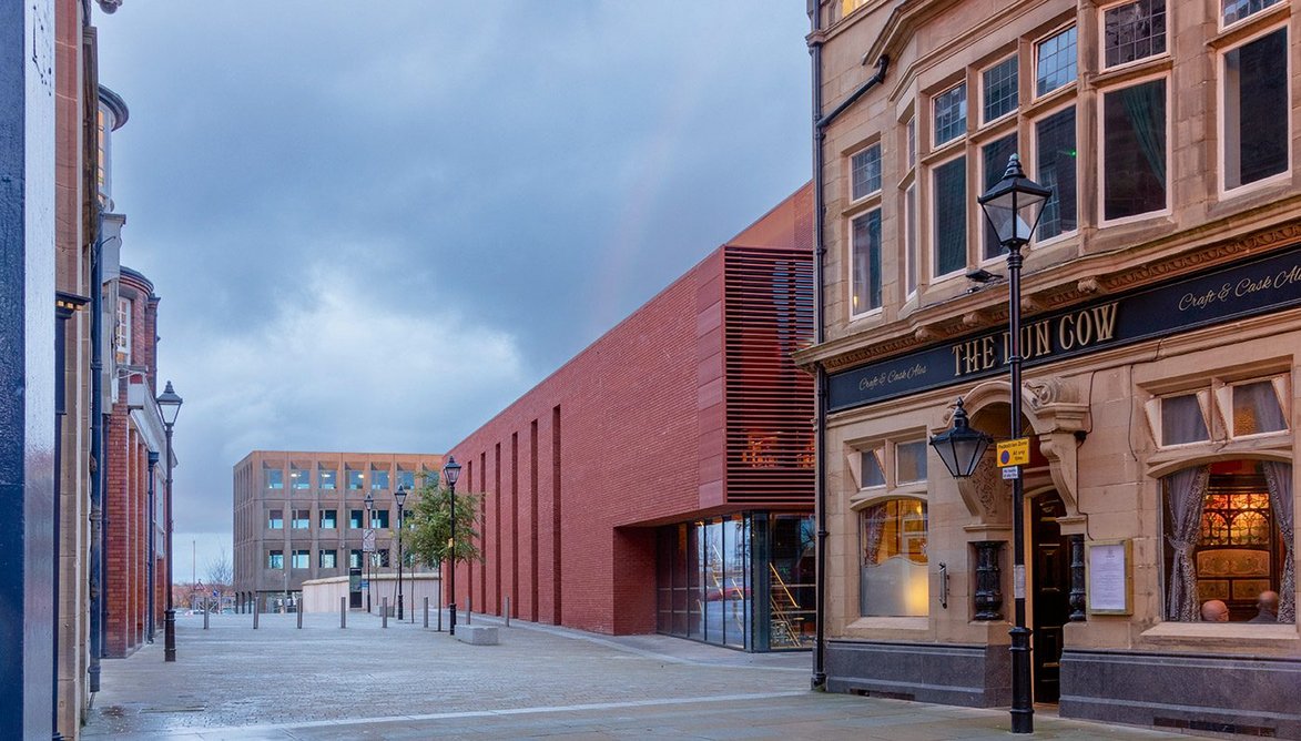 The west elevation of the auditorium presents a largely blank face to the theatre opposite, mitigated by contextual use of red brick.