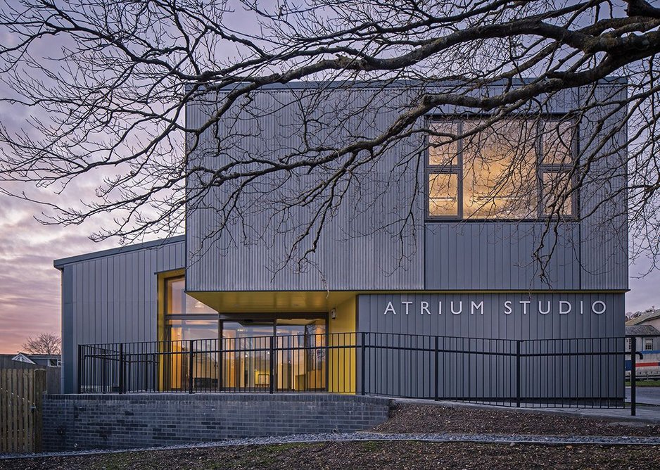 An entrance for students and industry, in glowing yellow below the fibre cement.