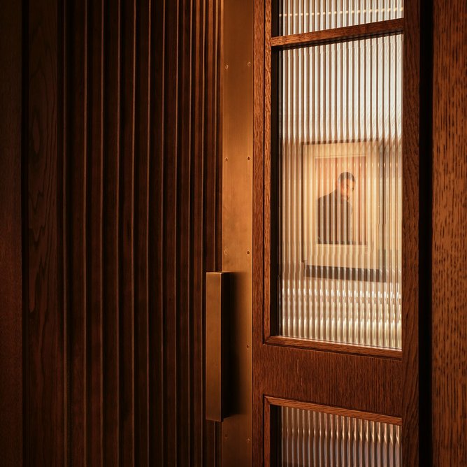 Vertical striations give the Italian travertine a more matt but no less luxurious quality. Elevator doors pick up on the brass theme.