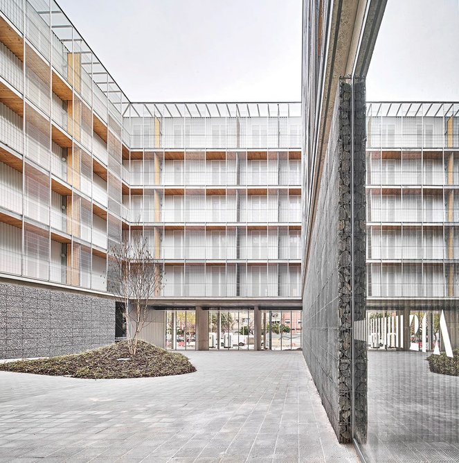 Modulus Matrix by Peris + Toral Arquitectes – gabion walls line the ground floor of the courtyard.