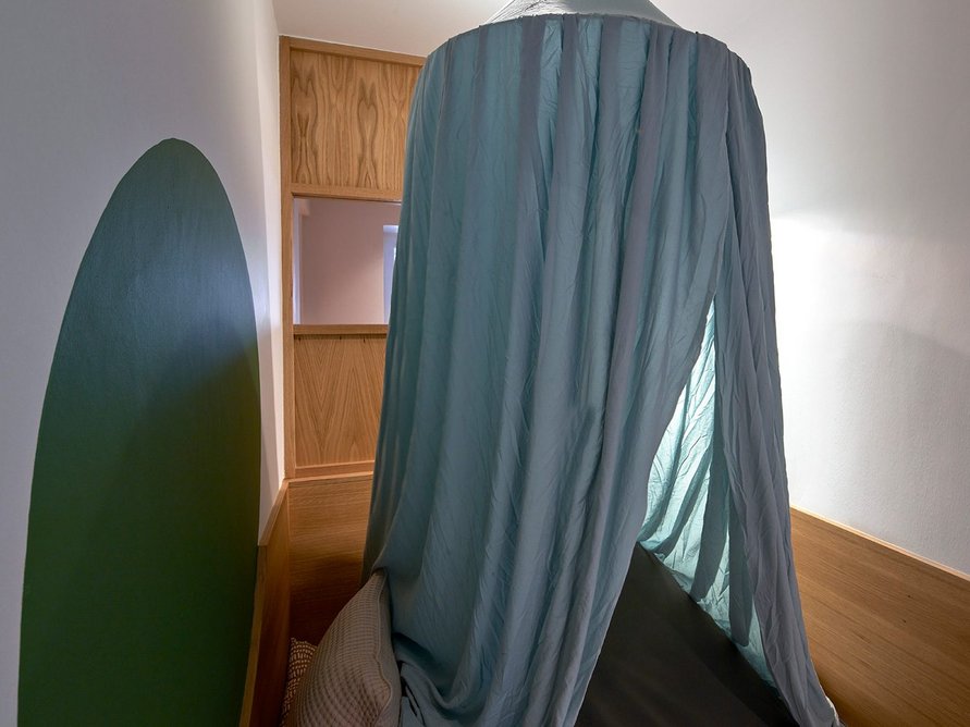 Cubby hole with tent above a raised platform, a place to feel enclosed. Sliding panels to one side can be opened up for partial views or a wriggly route out.