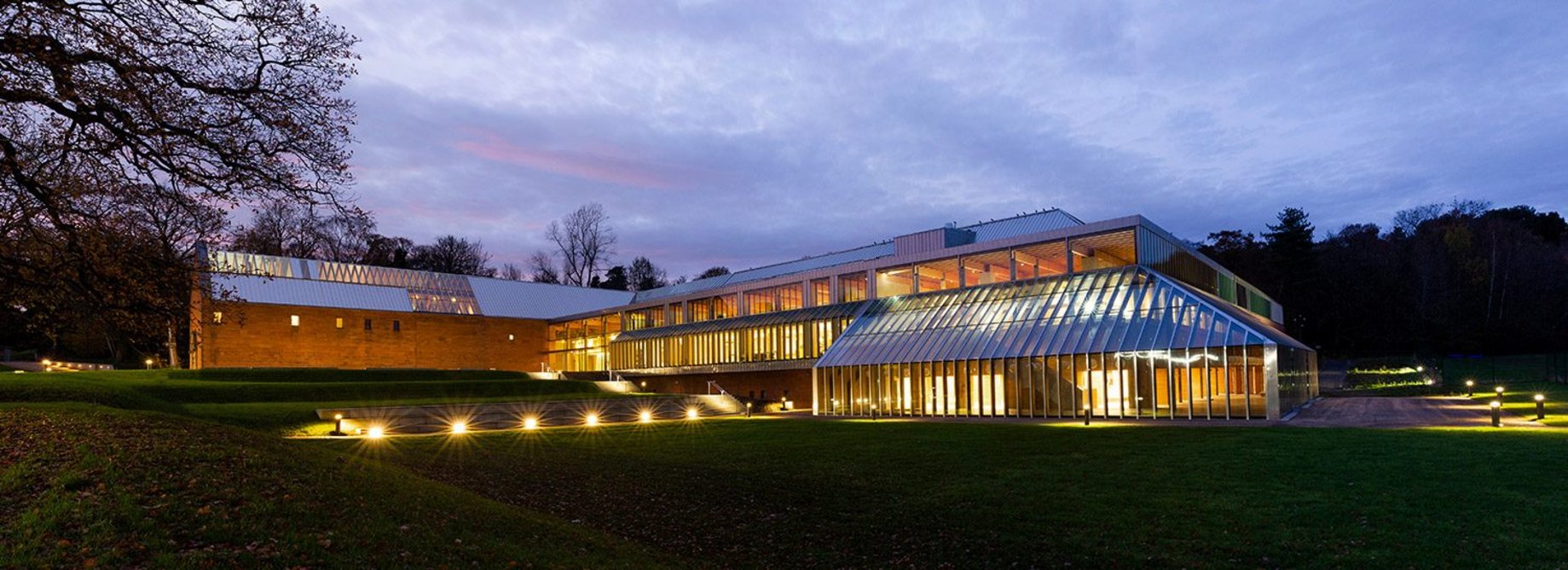 The stepped site of the Burrell Collection. The original entrance stretches out to the left (south); the new is where the glazing meets the stone. In the foreground the conservatory houses a café onto the park.