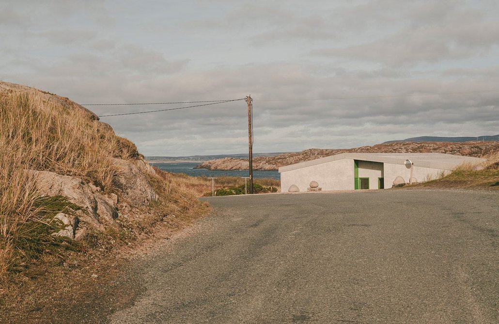 The house sits below a crest on a quiet island road.