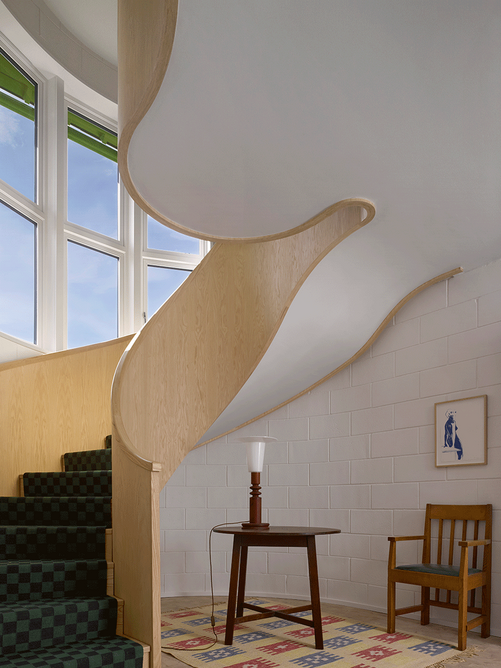 On the first floor, the stair banister flares to form a niche space with views over fields.