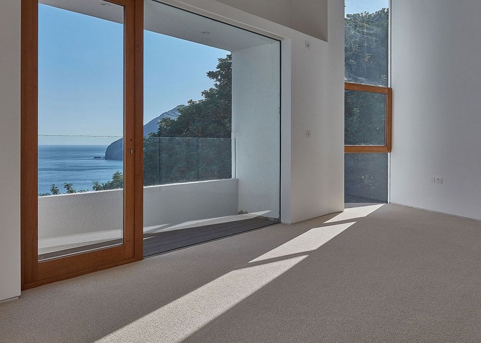 Timber frames around doors and opening windows helps define them in within the glazing. Here in the master bedroom.  Stealth House, Devon by Guy Greenfield Architects.