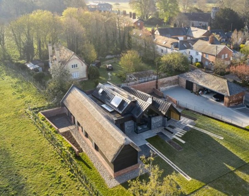 The thatched barn is wrapped in painted timber boarding and houses the guest rooms.