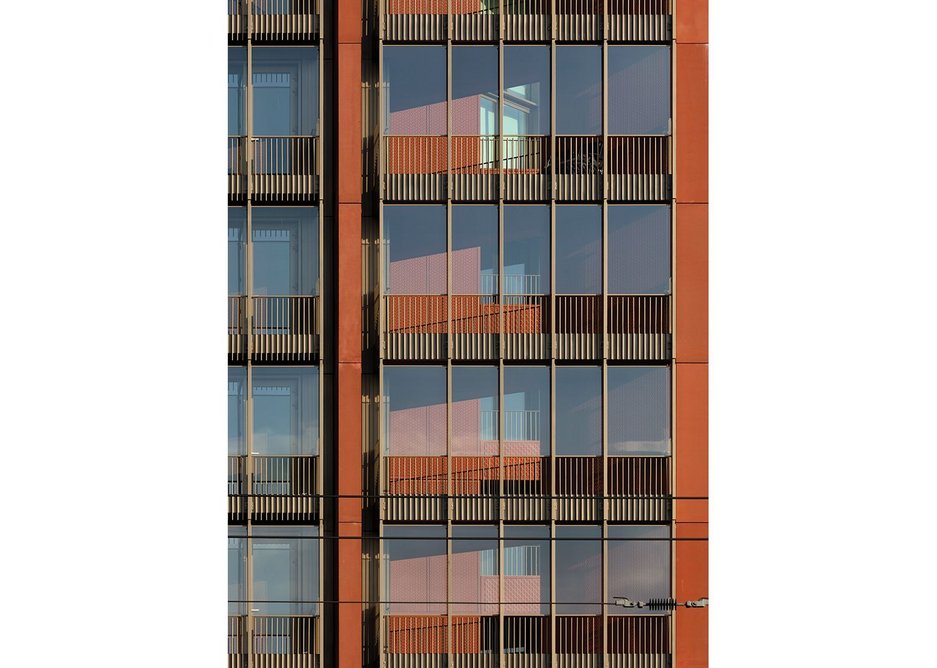 Detail of facade, with terracotta red cladding alongside Schueco glazing systems.