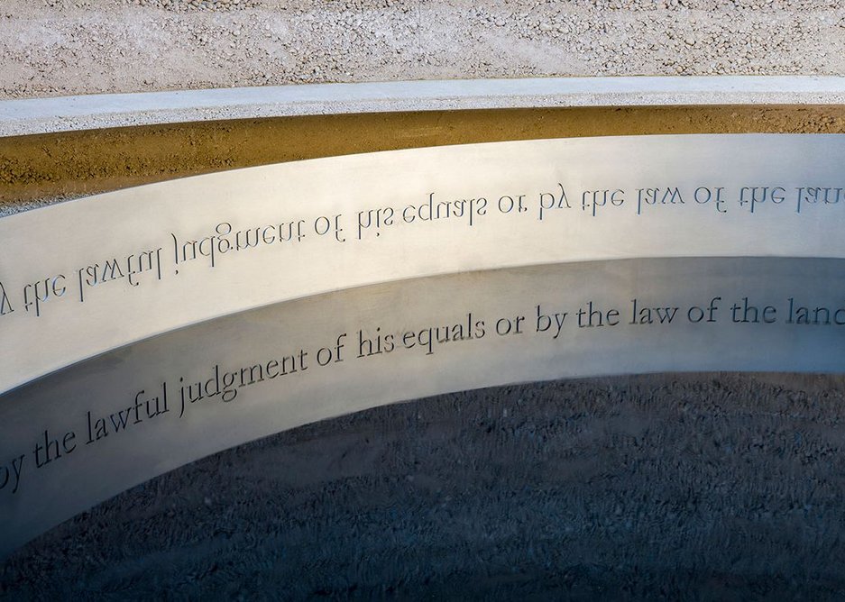 The words or Magna Carta clause 39 are legible in reflection in the water.