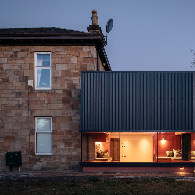 The frame-like character complements the solid presence of the existing sandstone building