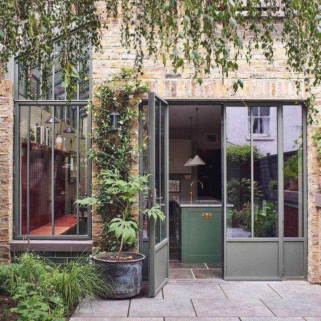 Glazed side return extension in verdant green steel brings light, life and lushness to a Clapham terrace