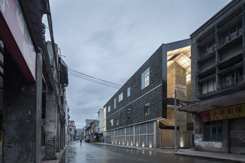 Lianzhou Museum of Photography Lianzhou China – grey shingle from demolished houses with a dark schist clads the envelope as it reaches over from wall to roof.