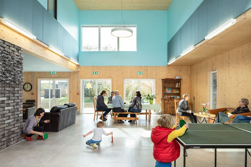 The high-ceilinged hall of the common house looks out onto the wild flower meadow.