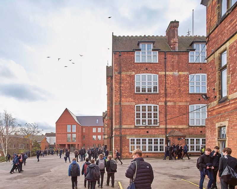 The school yard now has a visual end-stop in the form of the new building with its entrance arcade. Original 1880s buildings in the foreground.