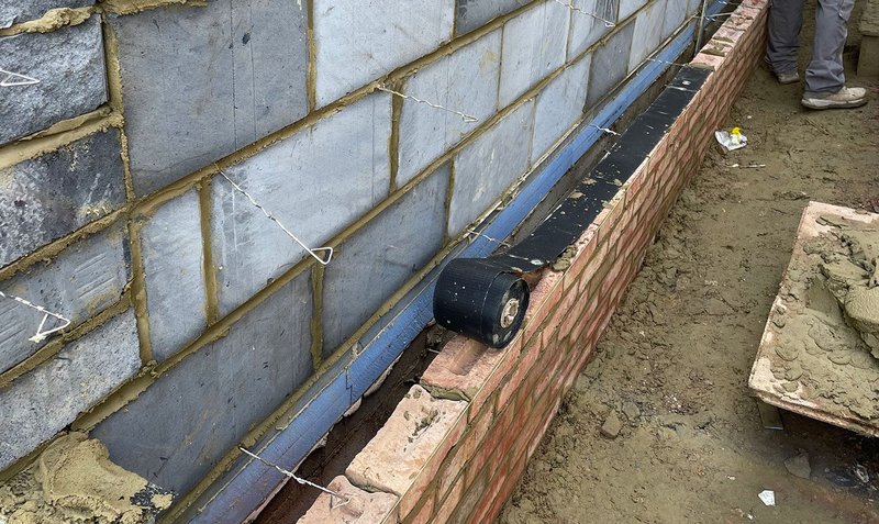 Load-bearing insulation (in blue) at floor-to-wall junction, and metal ties prior to being replaced with low-conductivity ones.