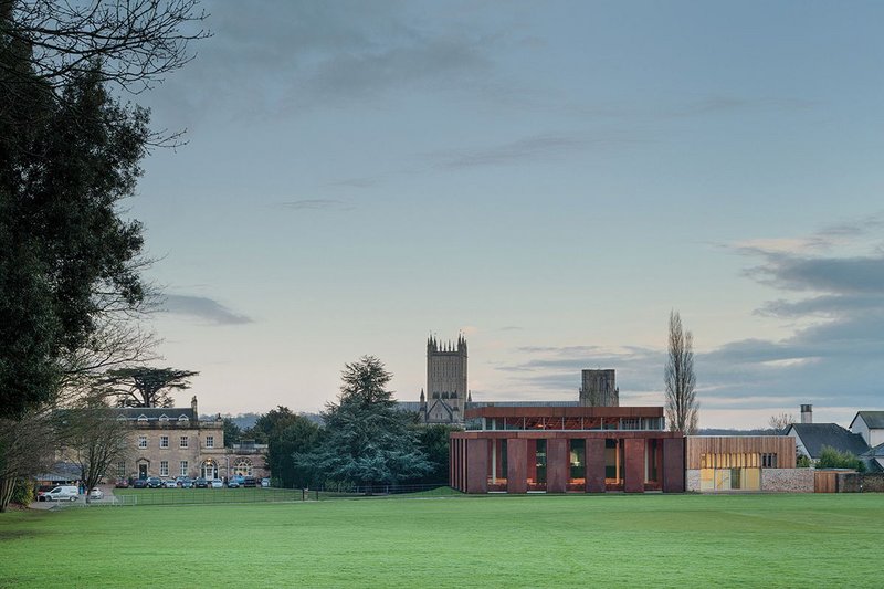 From across the cricket pitch the importance of sinking the volume of the hall into the ground, and reducing the massing at clerestory level, is clear. Left is the school’s reception, right are red timber-clad music practice rooms.