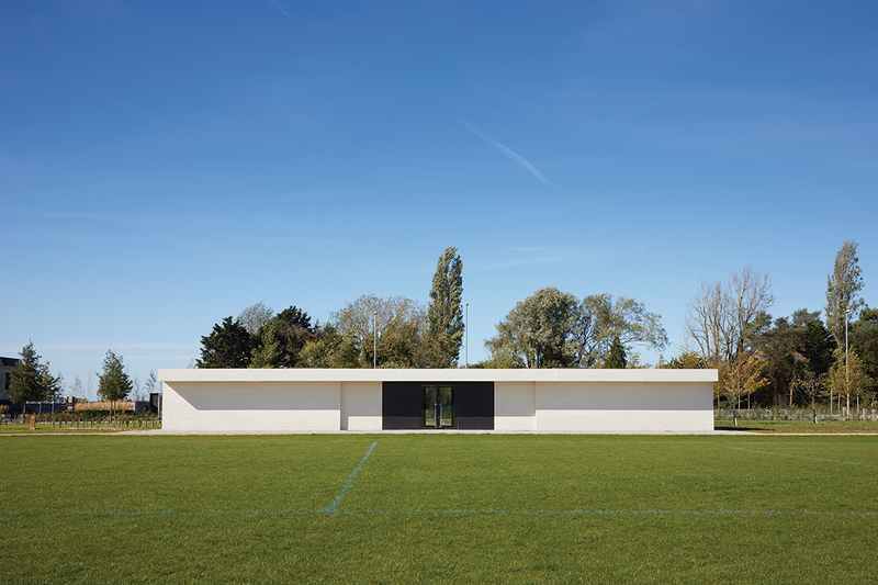 The sports pavilion sits on the edge of a large playing field with four changing rooms and eight WCs. Its facade is pushed and pulled to make it welcoming.