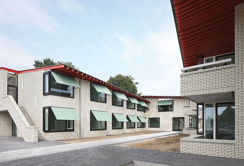 The south elevation of the complex where the dementia care facility, left, faces out to the one-bedroom sheltered housing. Bold green window awnings make way for large sheltered balconies.