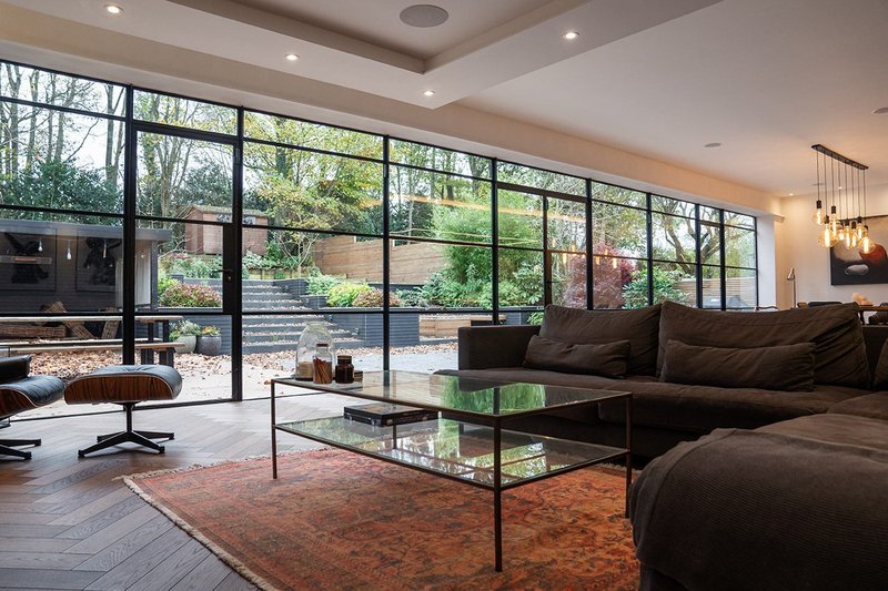 A pair of Crittall French doors, two single opening doors and fixed lights make up the glazed screen that connects the indoor and outdoor areas at a new-build home in Prestwich, Greater Manchester.