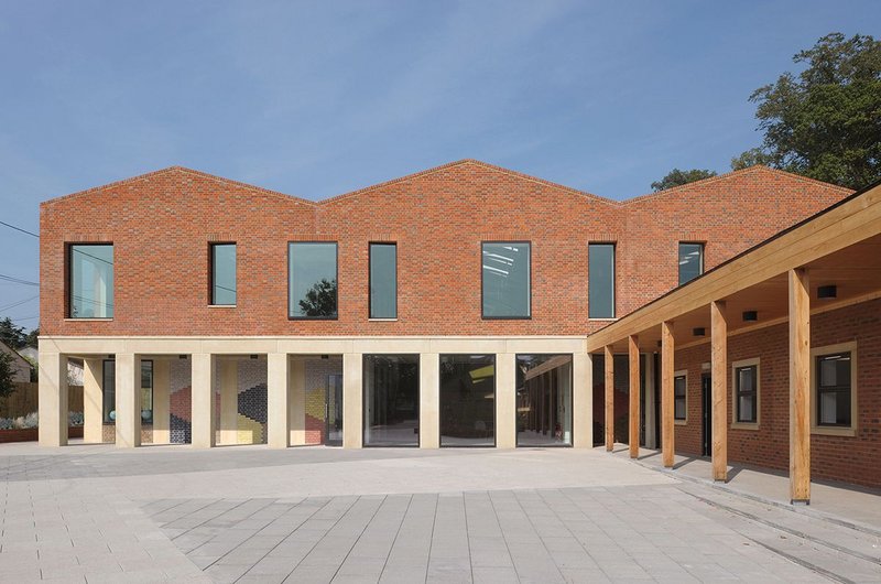 An existing adjacent block (now staff room), with its new timber colonnade and extended roof line, becomes part of the cloister composition and helps frame the playground area.