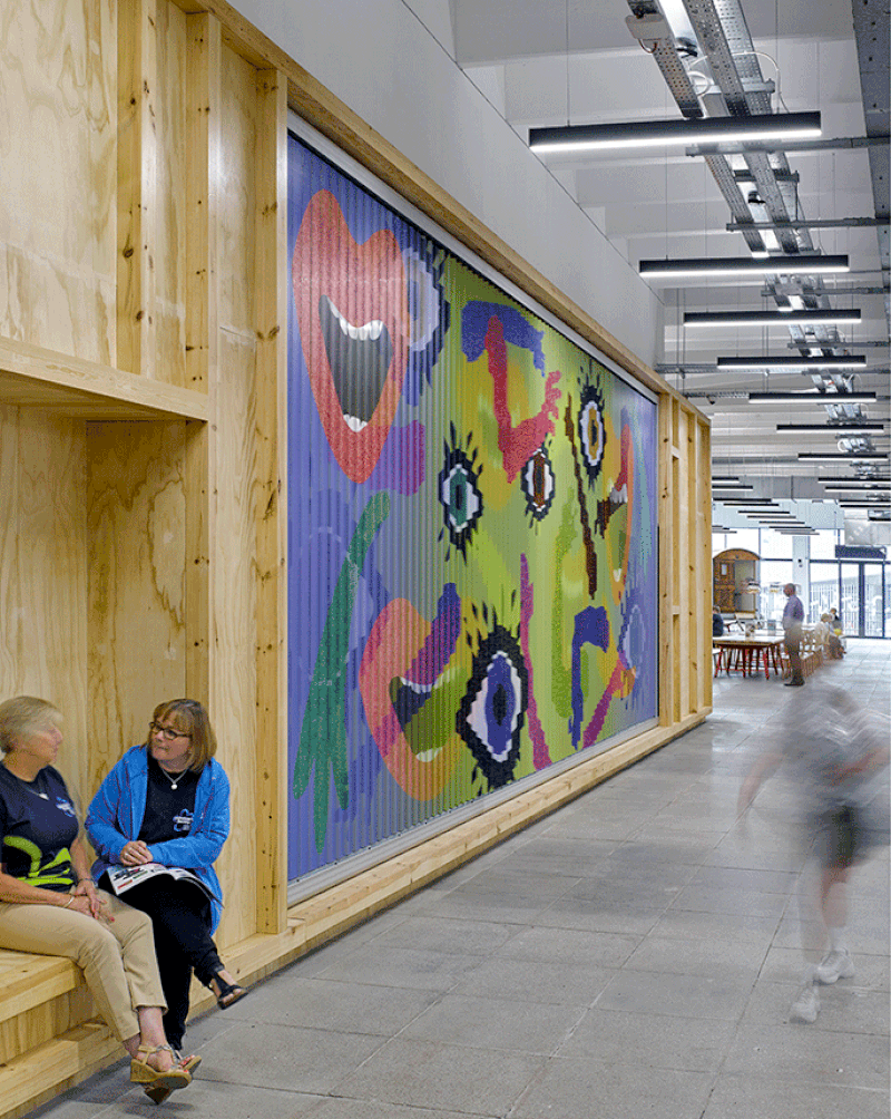 The ‘People’s Wall’ is a trivision billboard featuring work by artists with the community. Integrated seating allows shoppers to ‘inhabit’ the wall.