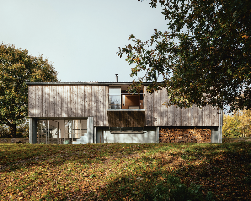 A folding balcony overlooks woodland that drops into the valley to the south of the building.