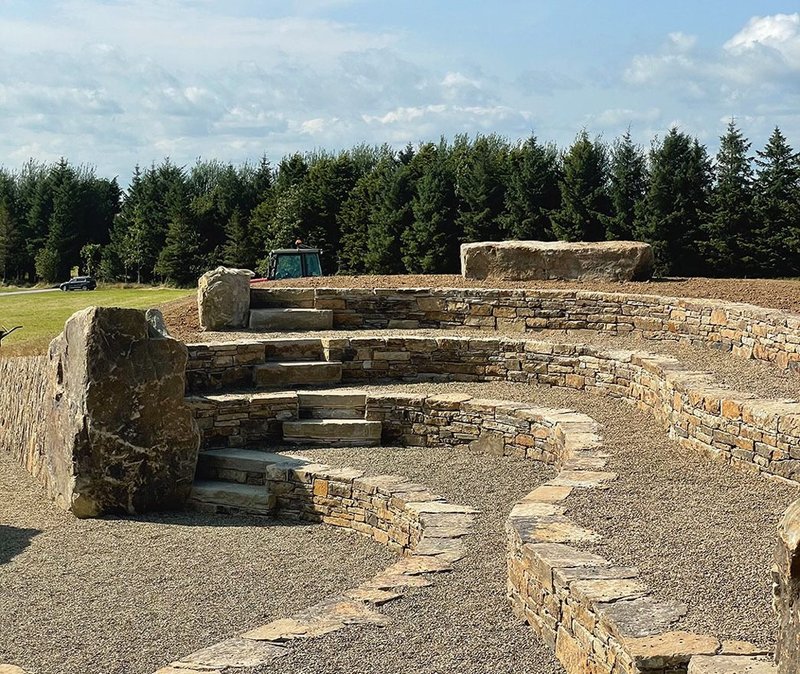 Hedge Theatre, which completes the trilogy, is entered via a gravel path slicing through raised  ground, with walls of vertically stacked stone.