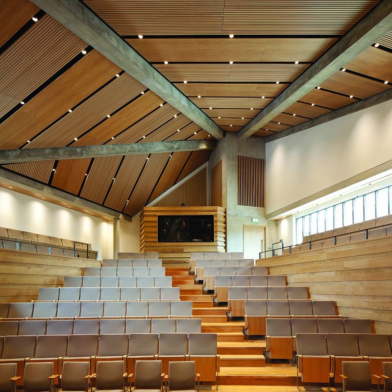 Dramatic concrete beams span out from the ventilation tower. There are awkward spaces between auditorium and rectangular envelope – but not too many.