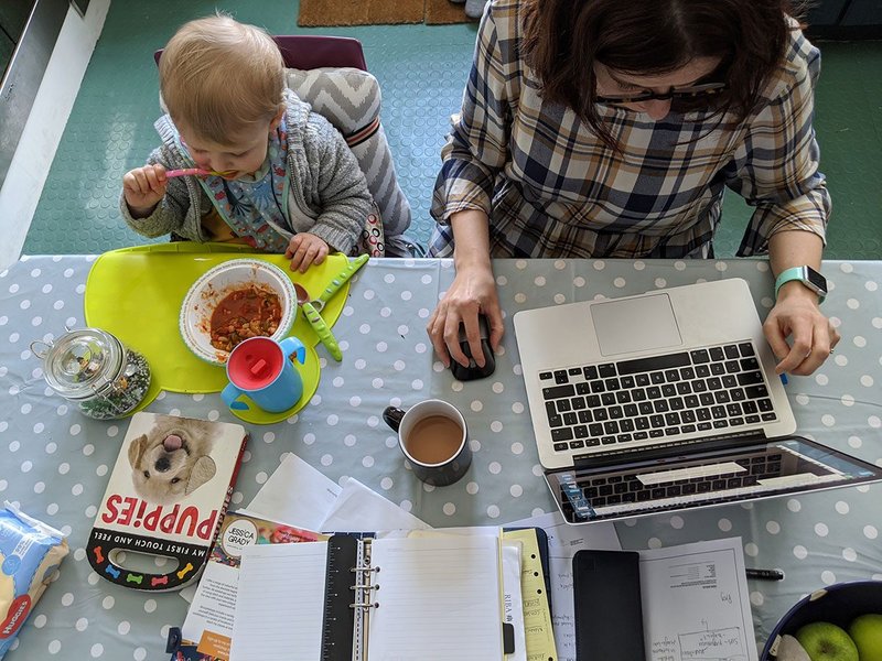 Stefanie Stead working at her kitchen table with Joseph during lockdown.