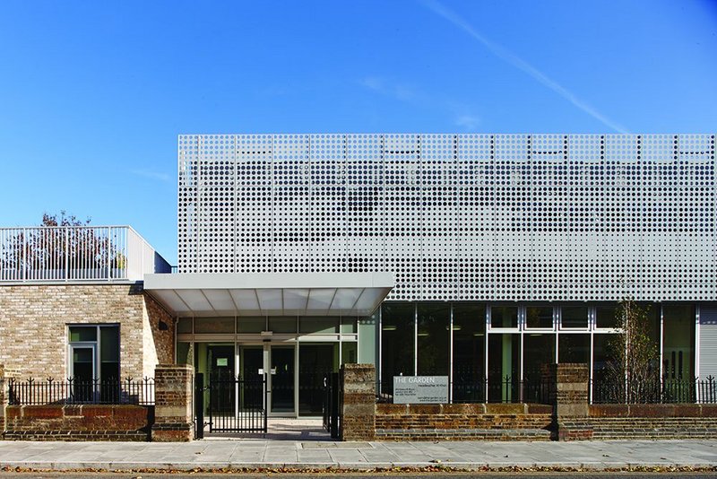 A punched facade unifies staff room and main hall above a more open ground floor.