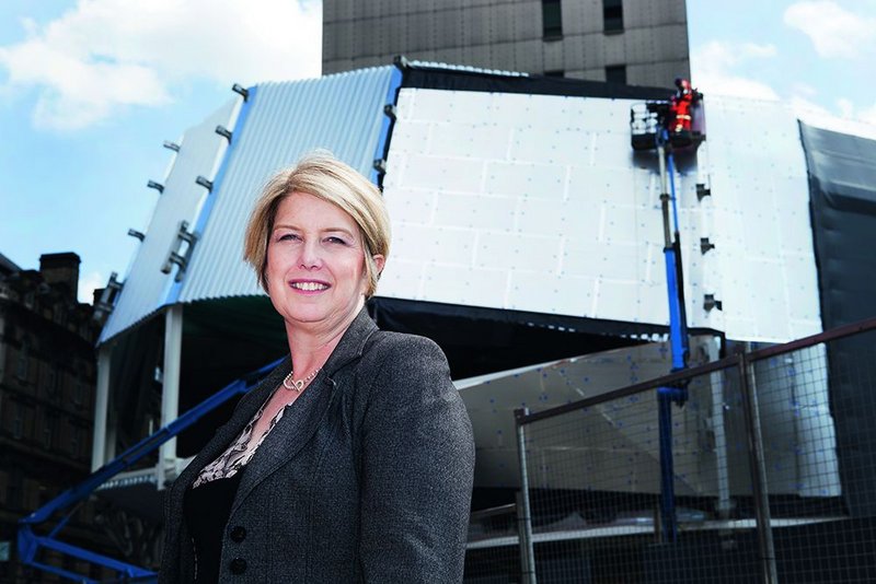 Carol Stitchman stands in front of the main entrance of the new New Street Station. Behind, the cladding framework that will support the building’s stainless steel ribbon facade.