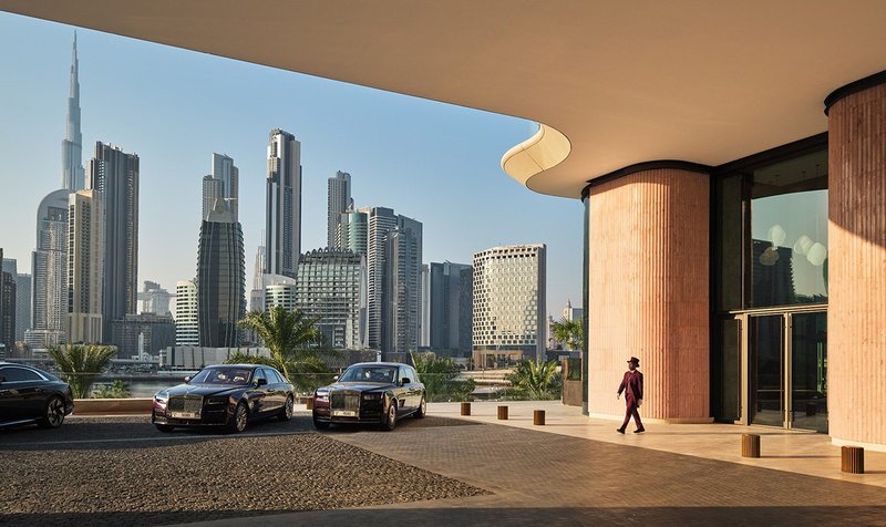 Covered hotel drop-off and VIP parking with a Dubai skyline view across the marina.