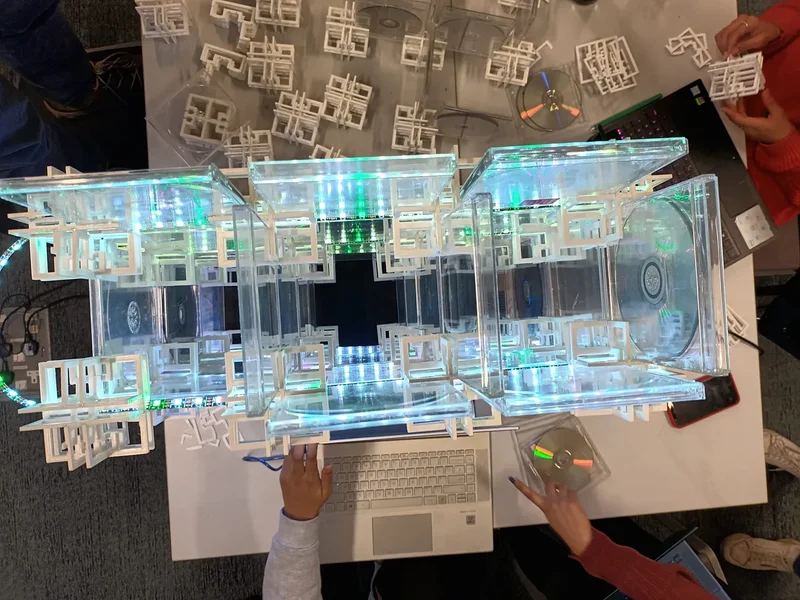 ‘Sensate Structure’ is a Year 1 module by Nottingham Trent University apprentices, constructed from waste CDs and 3D printed connectors made from modified corn starch. The apprentices experimented with coding to control a strip of LED lights which is threaded through the structure.  The module combines the circular economy, the relationship between structure and services and the use of ChatGPT to develop the Arduino coding that controls the LEDs.