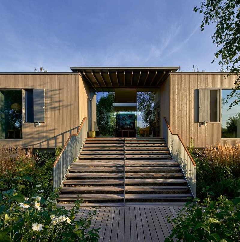 Glass doors open onto steps leading down to the river and jetty.