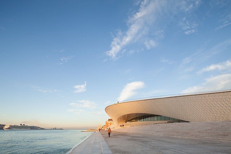 Lisbon’s MAAT gallery’s riverside elevation, looking west, the 16th century Manuelian style Torre de Belém in the distance. Click image to view