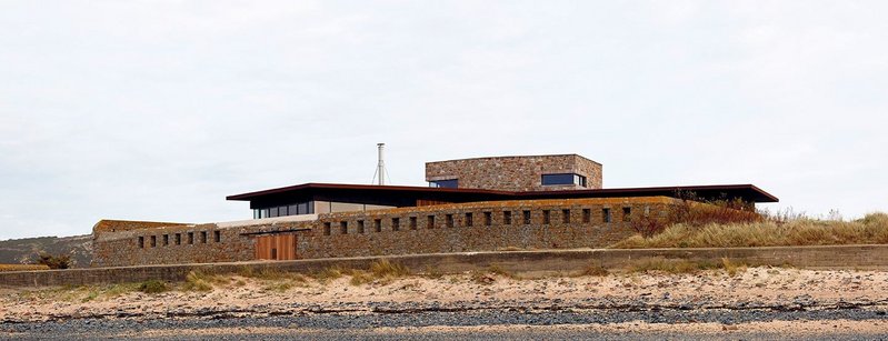 Beach view of the house, with the granite ‘keep’ rising above the two wings.