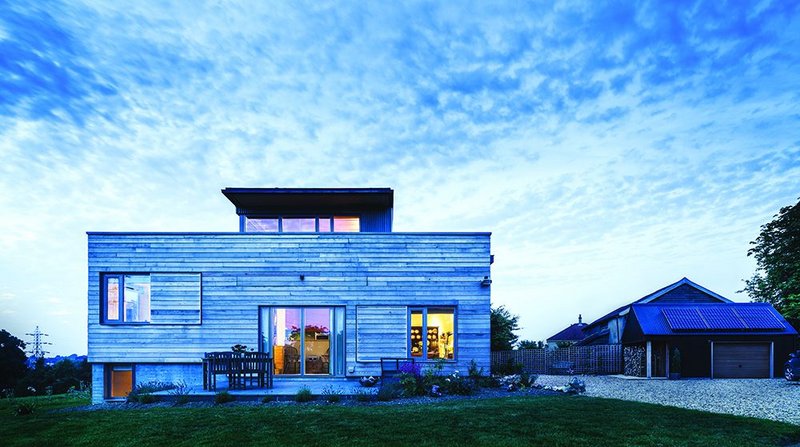 South elevation of Stackyard House: the first floor main bedroom peeks over the parapet to the left, basement level bedrooms give views west down the valley. Sliding shutters on windows, manually operated, help mitigate solar gain.