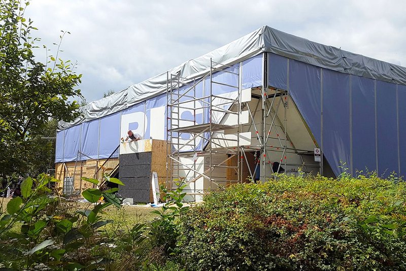 Scaffolding is clad in tensioned tarpaulin.