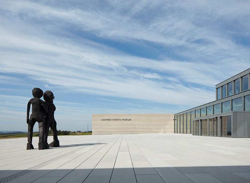 The stripped back, reconstituted stone plaza leading to the entrance foyer contrasts with the landscape around.