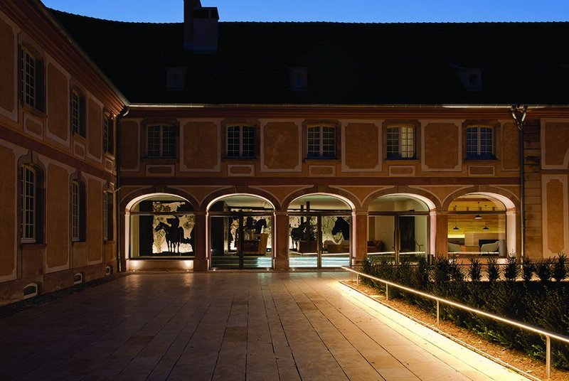 The colonnade of the hotel reception from the courtyard, with steel and glass equestrian mural to the rear