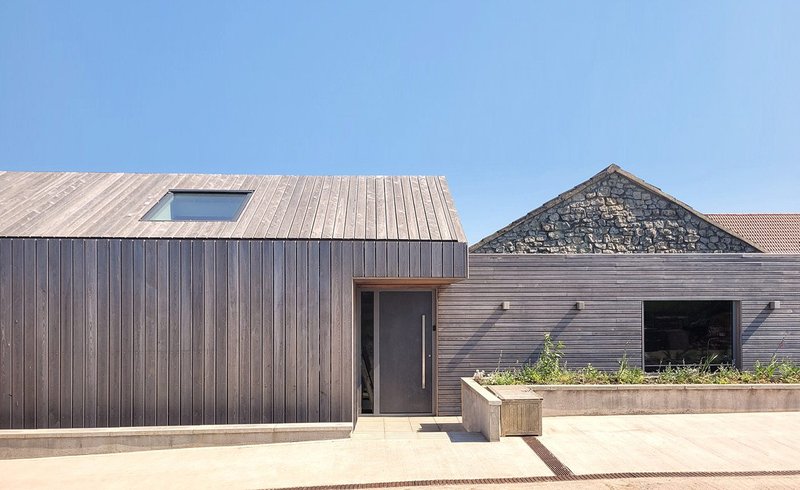 The extension to Old Barn, near Bristol, is entirely clad in larch, seen here projecting over the new entrance.