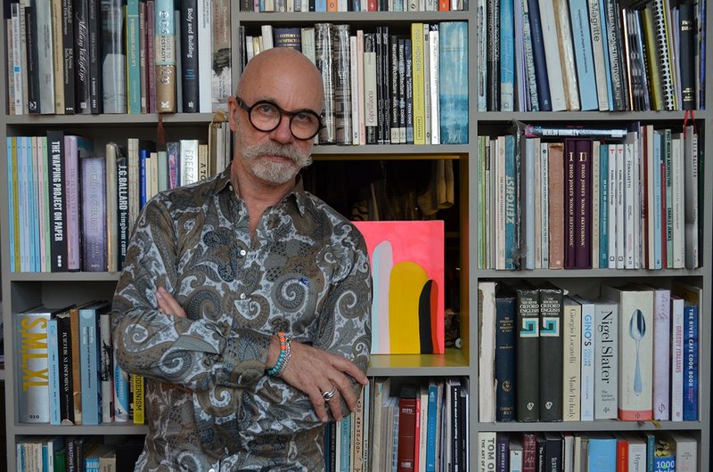 Nigel Coates at home in front of his bookshelves.