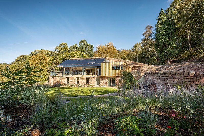 Quarry Stones House is visually conceived as a retaining wall with garden outbuildings – greenhouse and shed.