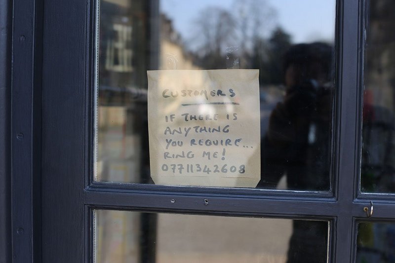 A notice in another shop window tells customers during lockdown to ring them if they need anything.