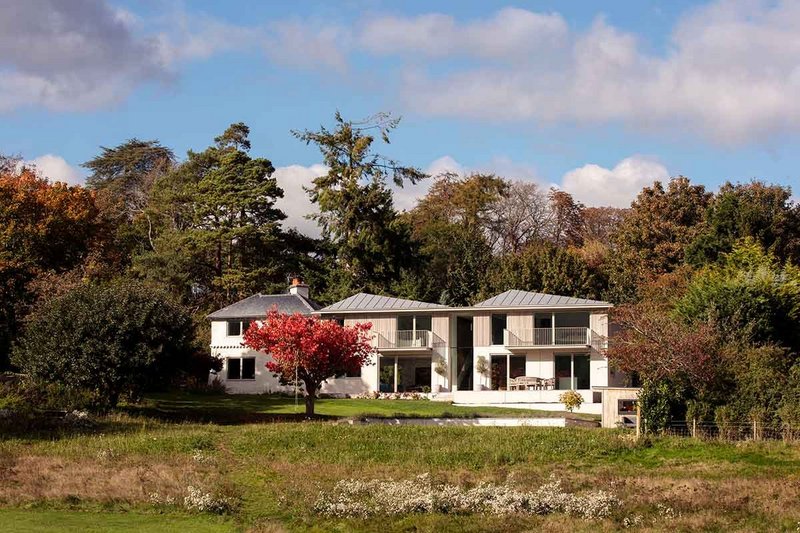 The house sits in a generous landscaped setting, the pool hidden in the foreground.