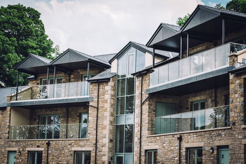 Q-railing balustrades at the Tall Tree Gardens development, Bolton-le-Sands: Glass and stainless-steel balcony railings perfectly match the stone and green surroundings.