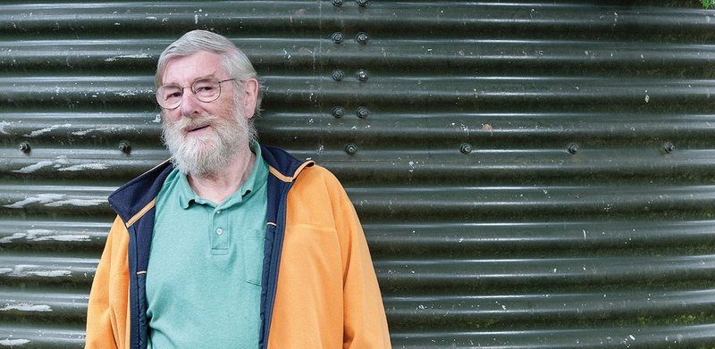 Peter Aldington in the oranges and greens he loves by the water tank of his garden borehole.